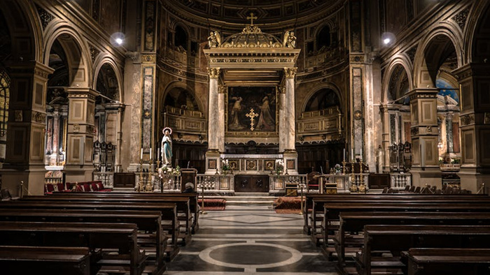 Basilika Vierzehnheiligen_Das Bild zeigt das Innere einer prächtigen barocken Kirche mit hohen Säulen und Bögen. Im Hintergrund befindet sich ein reich verzierter Altar mit Statuen und einem Gemälde. Holzbänke stehen in Reihen davor.